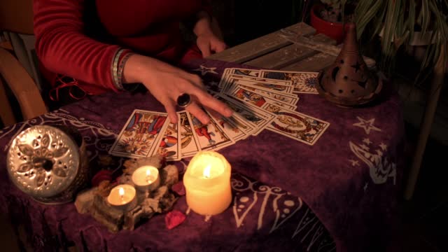Close-up of a fortune teller displaying some tarot cards on a wooden table