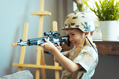 Little boy playing soldiers in living room. In his imagination the boy are defending the encircled city of Bastogne aganist the enemy.  Entertainment for kids indoors. Offline games.