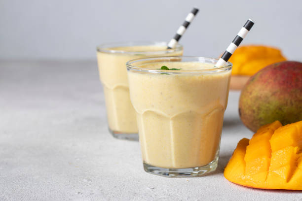 Mango lassi in two glasses on gray background with copy space. Freshness indian lassi made of yogurt, water, spices, mango and ice stock photo