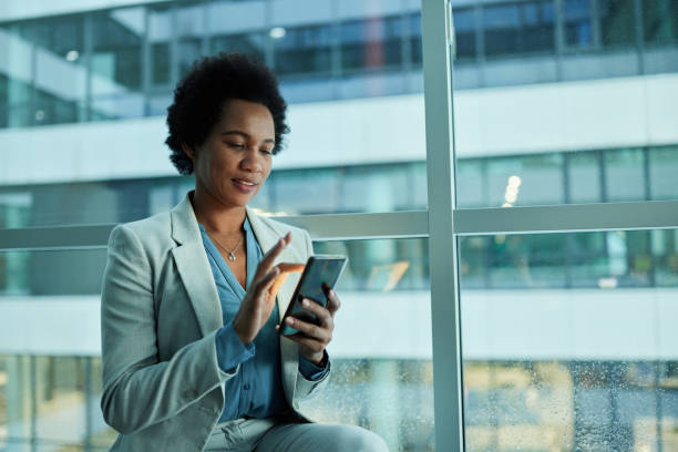 istock Black businesswoman using mobile phone by the window. 1397708953