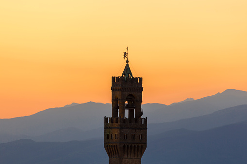 Sunset view at Palazzo vecchio tower in Florence with the mountains in background