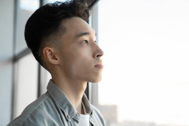 istock Young Asian man stands in office looking at panoramic window 1397710388