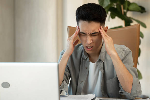 istock Asian employee holds head trying to solve difficult issue 1397710405