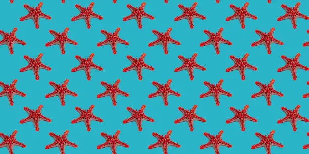 Seamless pattern of red starfish on turquoise background for wallpaper, fabric or wrapping-paper