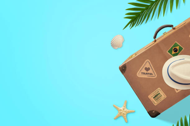 istock Retro suitcase and hat on blue surface with palm leaves beside. Top view, flat lay composition with copy space 1397713667