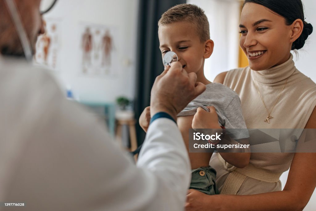 Lets have fun Mother holding son while doctor is performing examination using stethoscope Doctor Stock Photo
