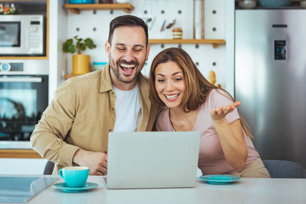 istock Happy young family couple bonding laughing using laptop looking at screen sit at table 1397716159