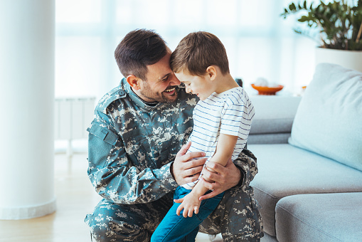Happy soldier play with his son. Soldier enjoying at home with children. My Hero is back home. Little boy meeting his military father at home. Memorial Day celebration\