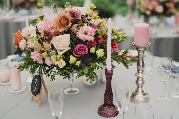 istock Table setting at the wedding reception. Floral compositions with beautiful flowers and greenery, candles, laying and plates on a decorated table. 1397718352