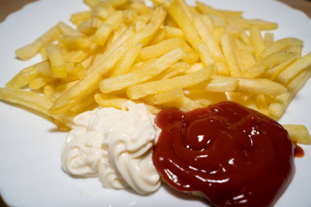 Fresh fried fries with ketchup and mayonnaise on a white plate