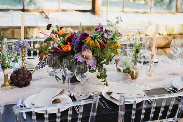 istock Table setting at the wedding reception. Floral compositions with beautiful flowers and greenery, candles, laying and plates on a decorated table. 1397719592