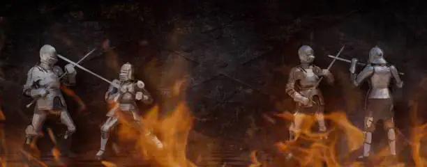 Photo of two knights in the ancient metal armor fighting in fire near the stone wall