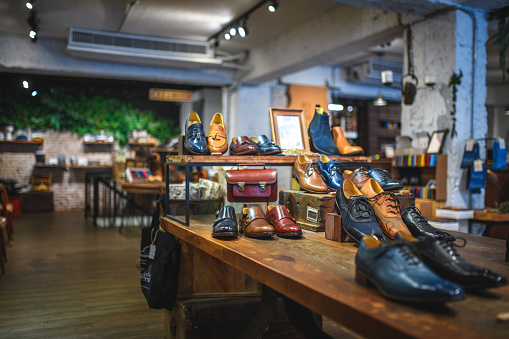 Display of unique shoe designs in natural leather at a luxury men's boutique. Casual and formal leather shoe models for work and social events. Boots, brogue and Oxford shoes for classic gentlemen.