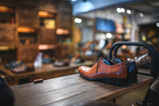 Fashion leather dress shoes for sale at a specialised handcrafted shoe store at the shopping mall. Display of casual and formal shoes for men on wooden shelves in a men's boutique.