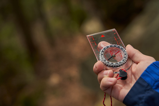 Backpacker keeping magnetic compass in hand while finding location in forest