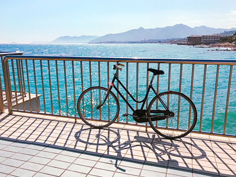 Panorama of the Ligurian coast with the sea and an old bicycle in a sunny summer day from the pier of Pietra Ligure, Savona, Liguria, Italy