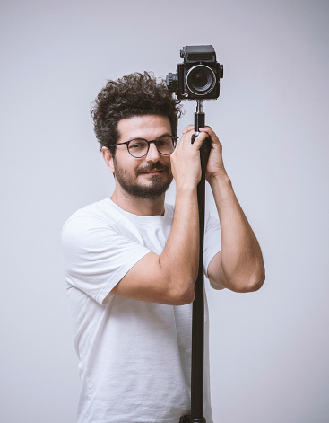 Photographer standing next to his camera, posing over white background