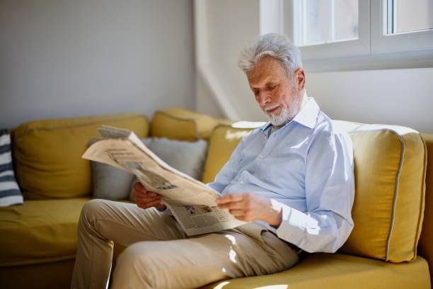 istock Elderly man reading a newspaper during a relaxing day at home 1397727493