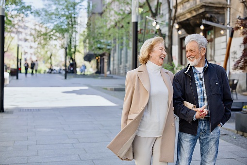 Smiling cheerful old man holding a hat and sitting next to his wife stock photo