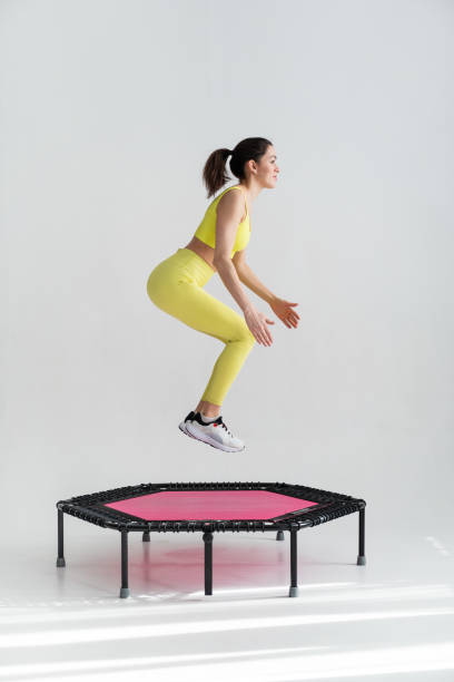 young fitness woman In sportswear jumping on sport trampoline stock photo