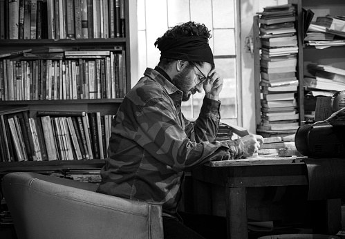 Mid adult man working and reading in his library