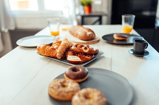 A table with pastry, orange juice and coffee set up for breakfast at home