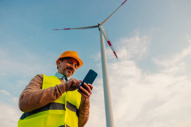 ingénieur masculin utilisant un téléphone portable à l’extérieur - engineer wind turbine alternative energy energy photos et images de collection