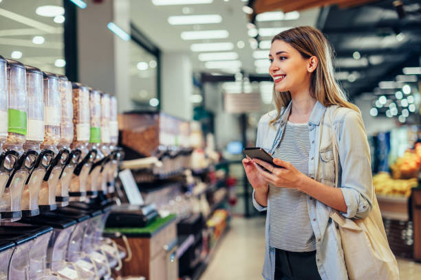 istock Young woman in grocery using phone 1397733460