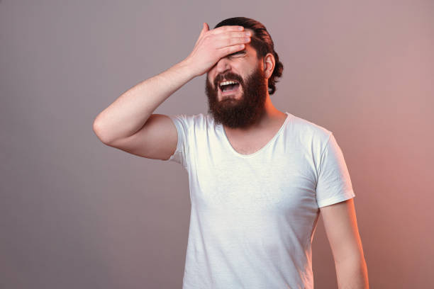 Distraught bearded man is giving himself a facepalm as he forgot something. stock photo