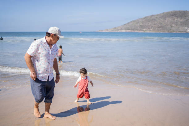 istock Little boy walking with grandfather at the beach 1397736072