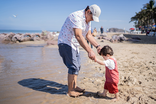 Little boy being helped by grandfather at the beach