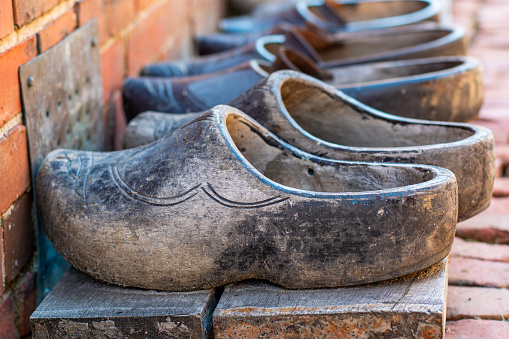 Pairs of old used dutch traditional wooden shoes or clogs in a row.