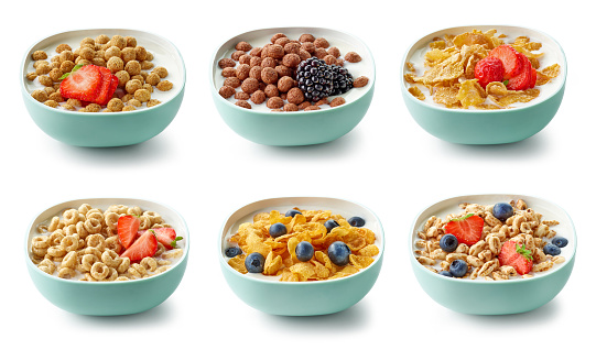 various bowls of breakfast cereal with milk and berries isolated on white background