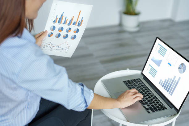 istock self employed, business owner, pleasure from work, Asian woman using computer holding financial documents to check or plan budget, manage investment risk at home. 1397742920