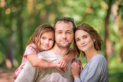 Portrait of a happy traditional family on a walk in a summer park, view from the back without a face