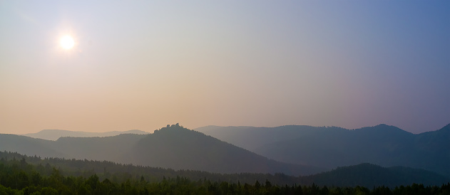 Mountain sunset landscape with heavy smog from forest fires over the siberian taiga. Panoramic view on Krasnoyarsk Stolby National Park in smoke