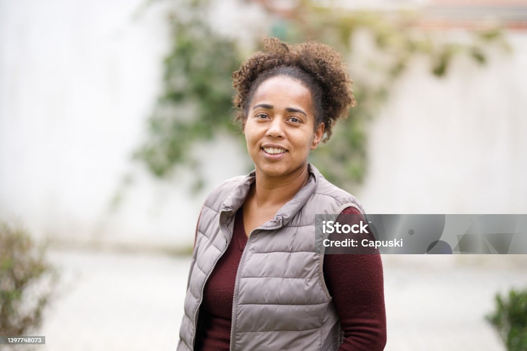 Coiled hair woman smiling and wearing a padded vest Family going to see the doctor 30-34 Years Stock Photo