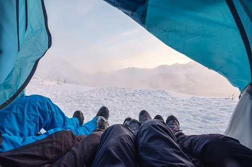 Climber legs resting in a tent among the blizzard on mountain peak