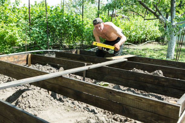 istock A man of mature years makes high beds on a personal plot. The master works with a level tool to maintain the correct dimensions of the boards. 1397752123