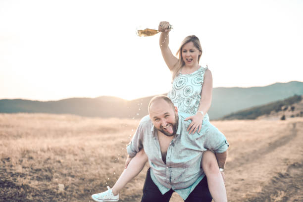 istock Crazy Male Getting Champagne Poured Over Head By Girlfriend While Carrying Her On Back 1397753527