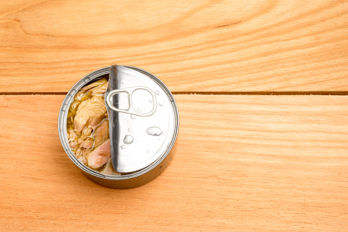 High angle view of can of tuna fish in oil over wooden table in the kitchen