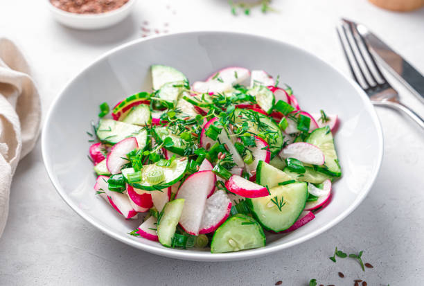 istock Fresh vegetable salad with radish, cucumber and fresh herbs on a light gray background. 1397755642