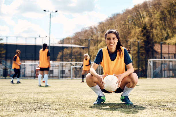 Portrait of happy female soccer player during sports training on playing field. Portrait of happy woman with a ball during soccer training on playing field looking at camera. womens soccer stock pictures, royalty-free photos & images