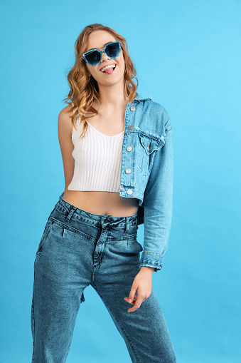 Cheerful young pretty girl in casual style outfit isolated on blue background. Concept of beauty, art, fashion, youth, sales and ads. Blonde woman posing, dancing. Looks happy, delighted