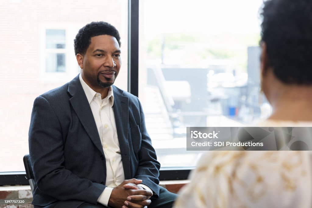 Mid adult man listens to therapist The mid adult man listens to the therapist during group therapy. Males Stock Photo