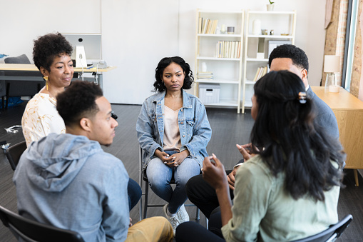 The young adults sit in a circle and participate in group therapy at the counseling center.
