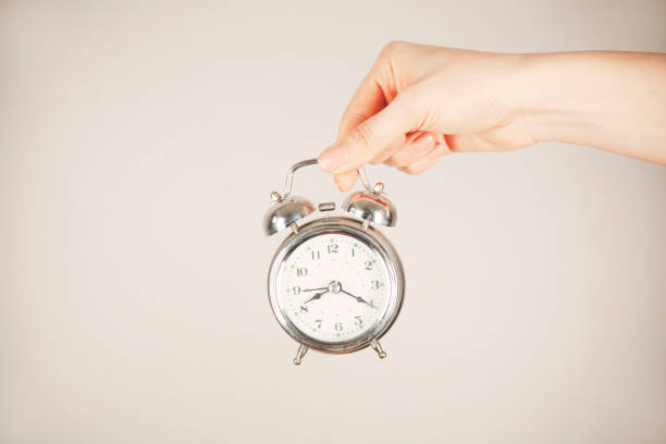 istock woman hand holding clock on gray  background 1397760857
