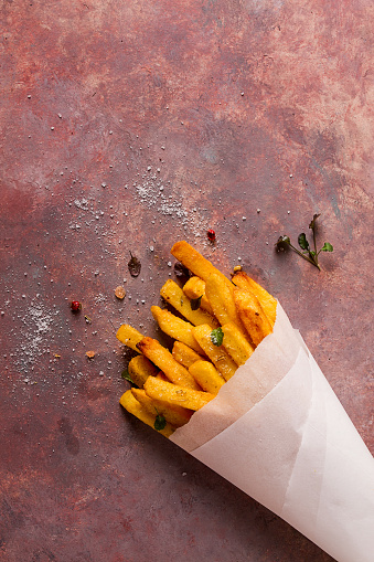 Fried French fries, in a paper bag, on an abstract background, no people, rustic,