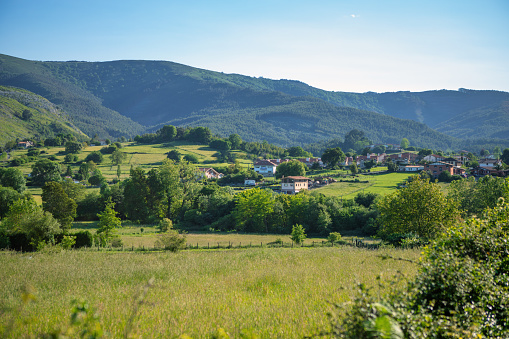 A small village at the foot of the mountain surrounded by greenery on a sunny spring day.