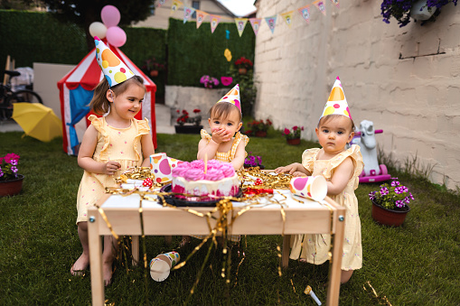 Twin sisters with an older sister celebrating their first birthday